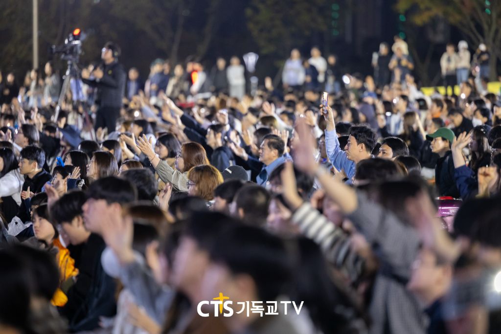 밤에 손을 들고 찬양하는 많은 회중